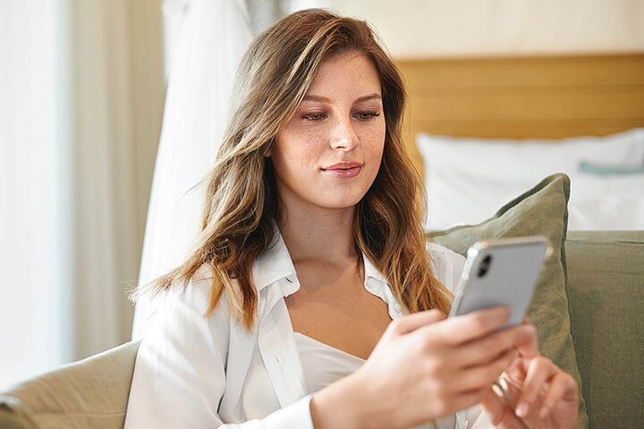 Frau mit Smart Phone auf dem Sofa