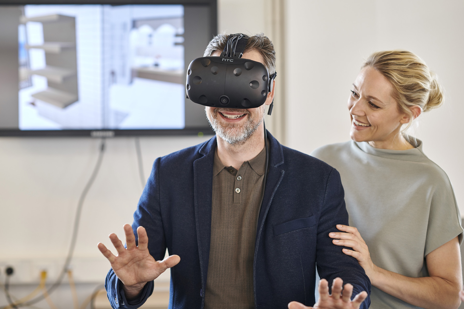 Mann mit virtuell Reality Brille in einer Badausstellung. Frau steht hinter ihm.